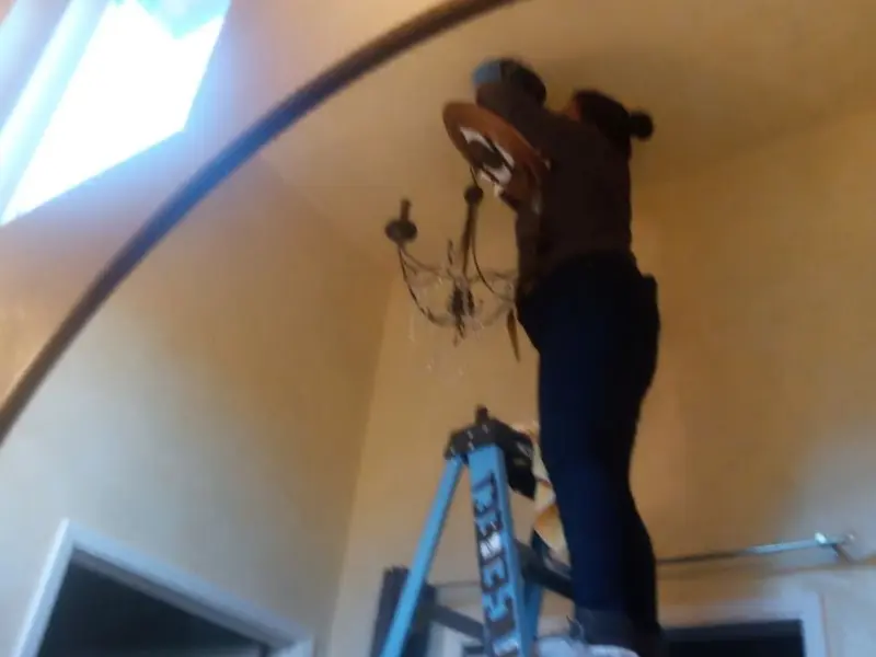 Electrician installing a chandelier in a DuPont residence